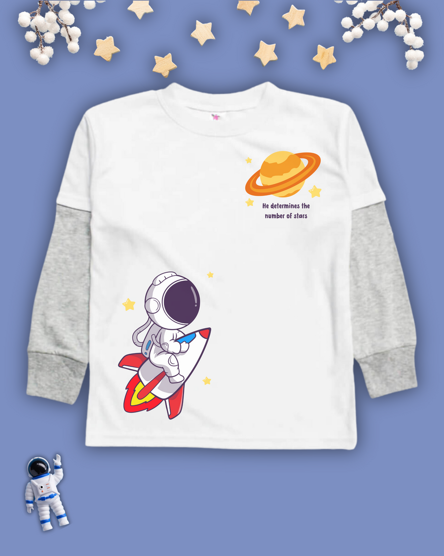 White kids Christian tshirt with gray long sleeve undershirt decorated with an astranaut riding a rocket heading towards a planet with the words 'He determines the number of stars" under it.