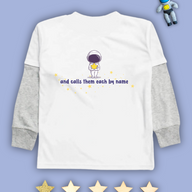White kids Christian tshirt with grey long sleeve undershirt decorated with an astronaut holding a star with the words "and calls them each by name" among stars beneath it. 