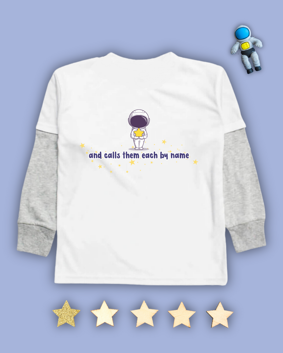 White kids Christian tshirt with grey long sleeve undershirt decorated with an astronaut holding a star with the words "and calls them each by name" among stars beneath it. 