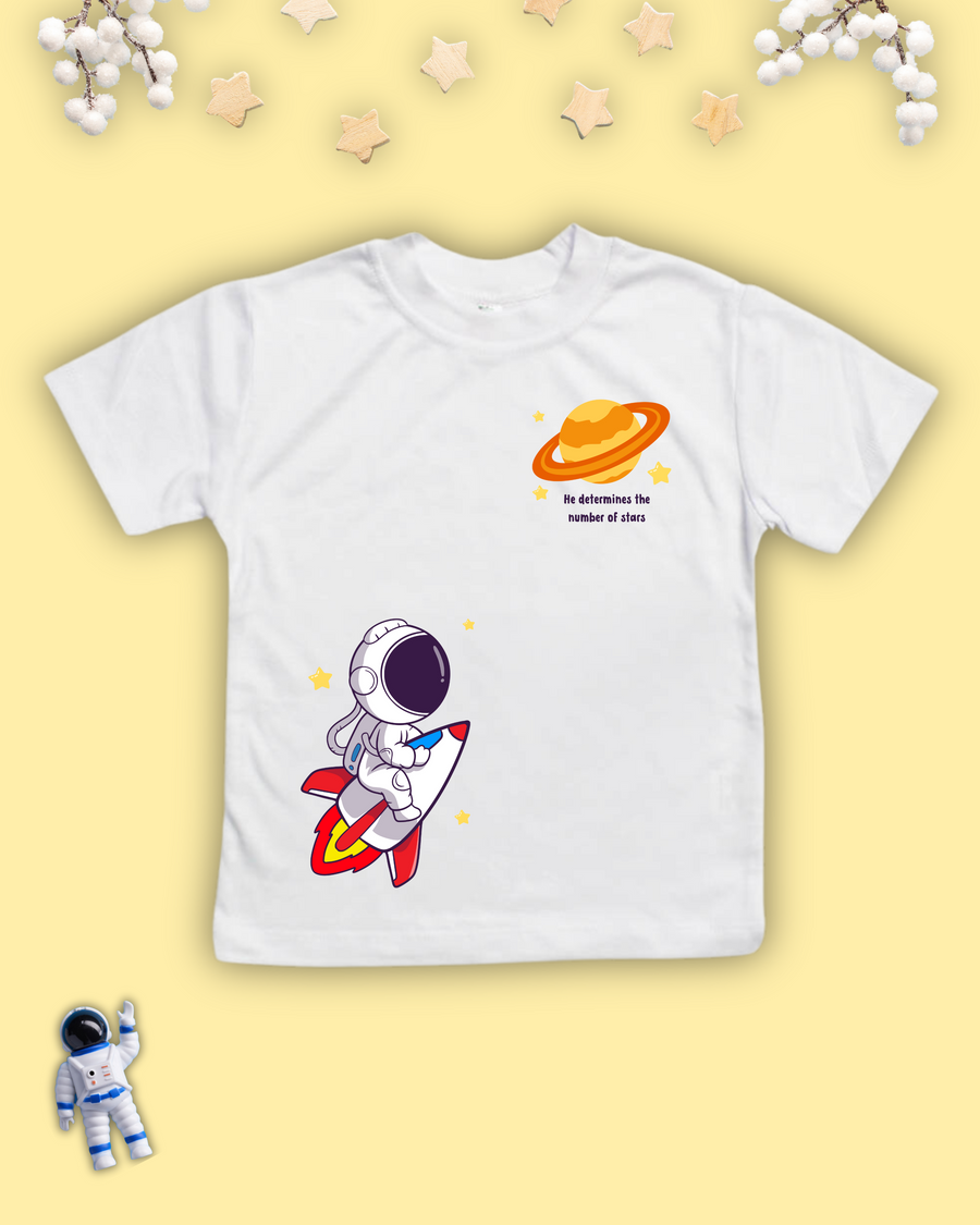 White kids Christian tshirt with an astronaut riding a rocket ship towards a planet with the words "He determines the number of stars" beneath it. 