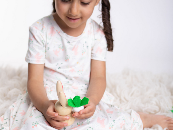 girl sitting on floor playing with a wooden bunny and carrot