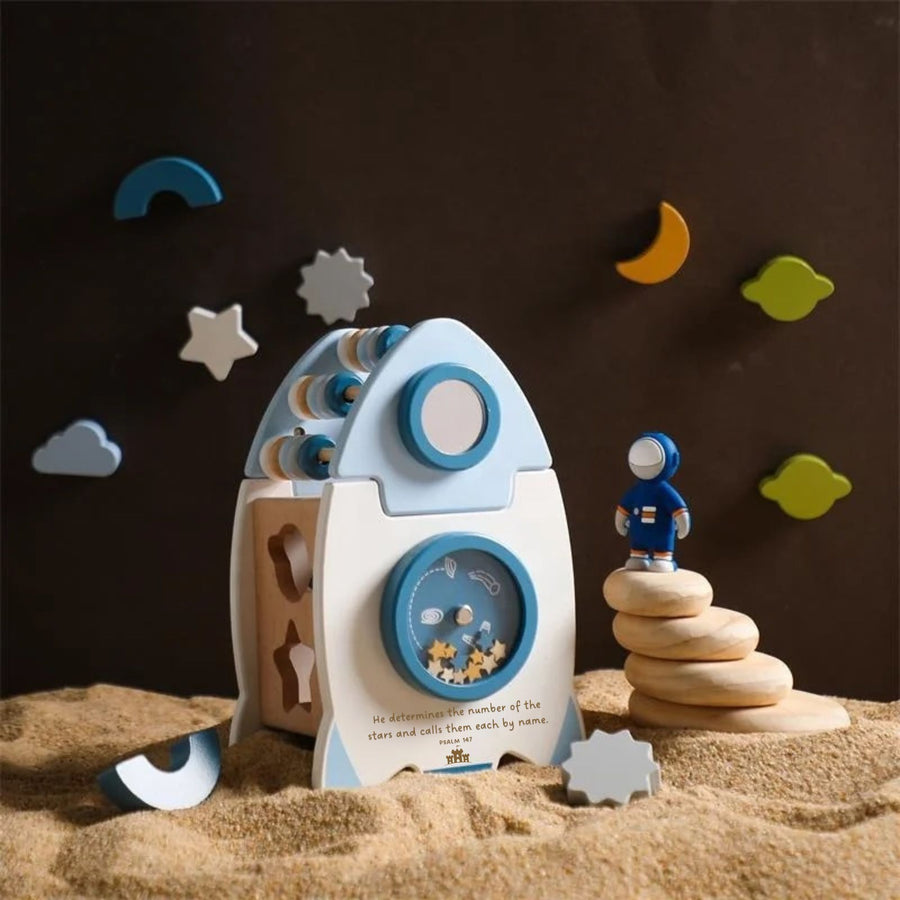 wooden rocket ship sorter toy with spinning wheel that contains small wooden stars.